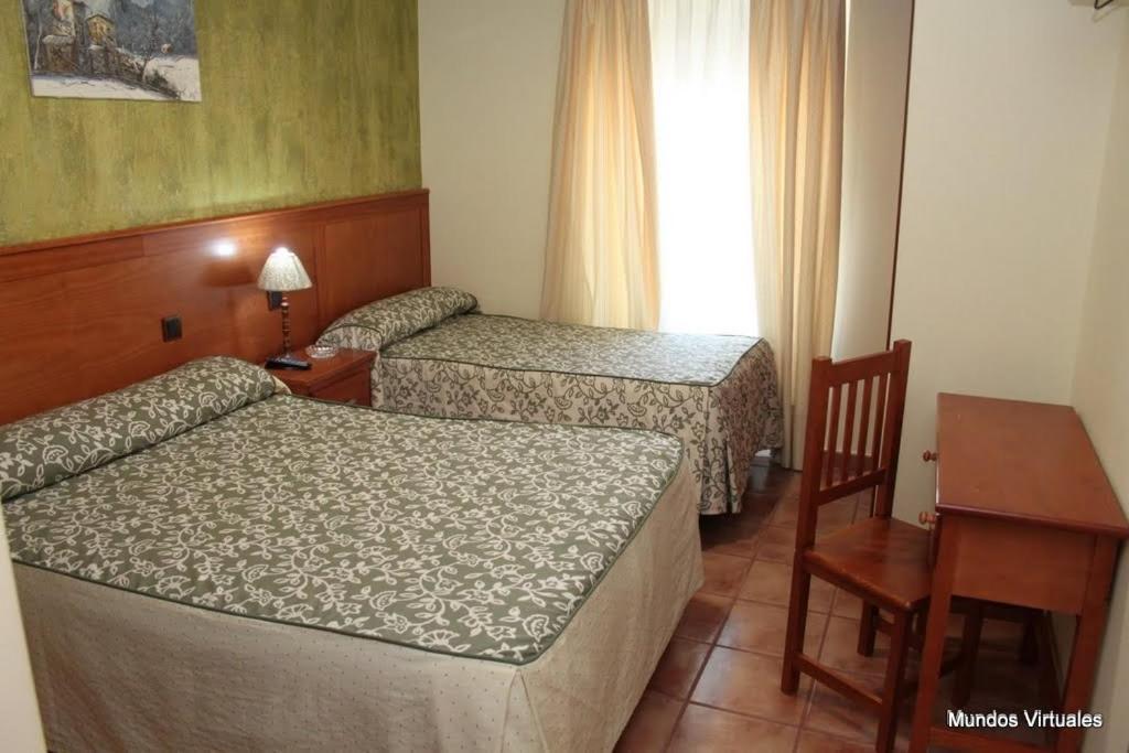 特鲁希略索尔保利诺旅馆的酒店客房设有两张床、一张桌子和一张书桌。