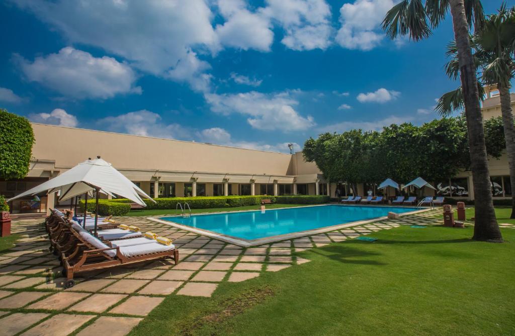 阿格拉提瑞迪特酒店的一个带躺椅和遮阳伞的度假游泳池