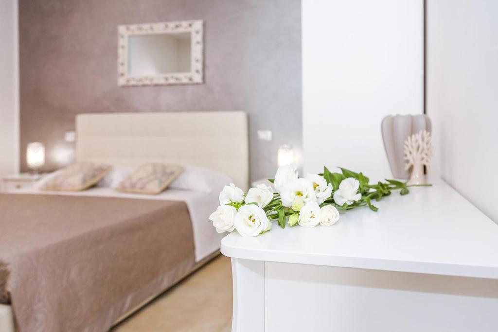 乌真托Il Lilium的一间卧室配有一张带白色花卉的桌子。
