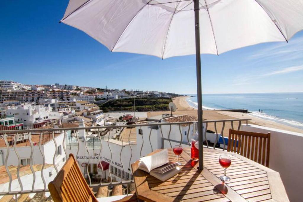 阿尔布费拉Casa T'Isabel - Fisherman's Beach - 2 bedrooms的阳台配有雨伞和带酒杯的桌子。