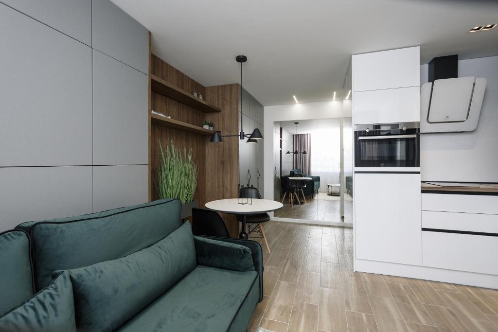 希奥利艾City Center Apartment in Siauliai的一间带绿色沙发的客厅和一间厨房