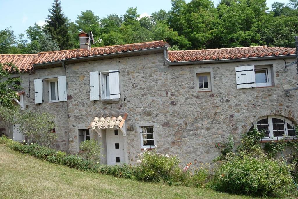 圣洛朗－德塞尔当maison en pierre dans un écrin de verdure的一座古老的石头房子,田野上设有白色窗户