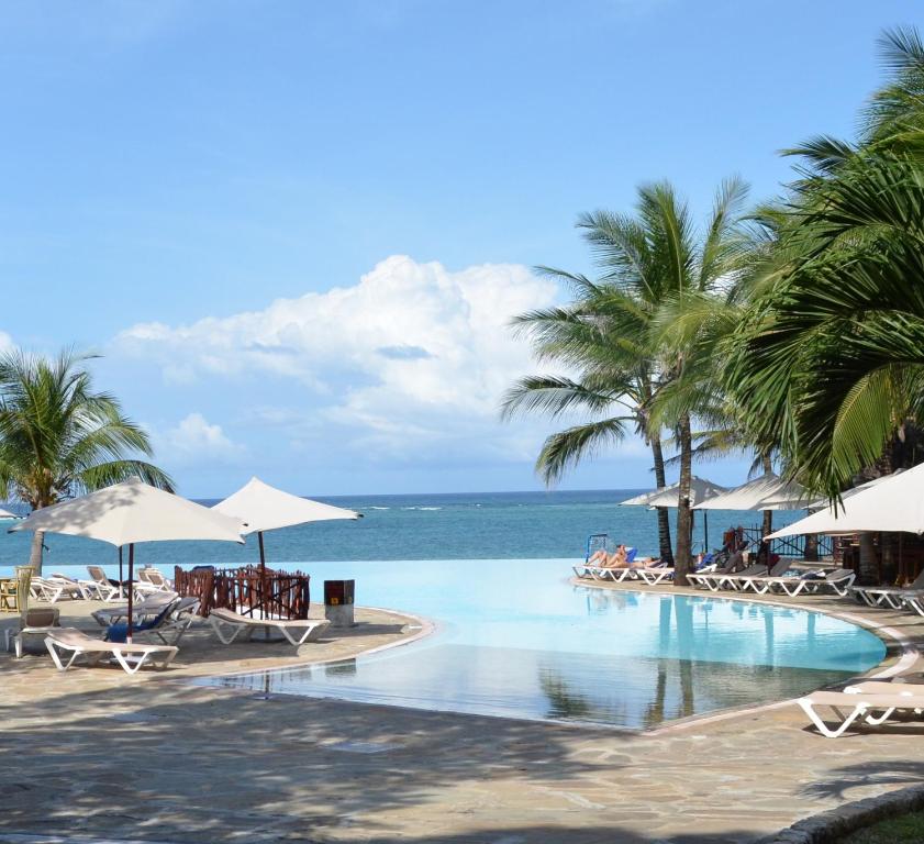 迪亚尼海滩保巴博温泉海滩度假酒店的一个带椅子和棕榈树的游泳池以及大海