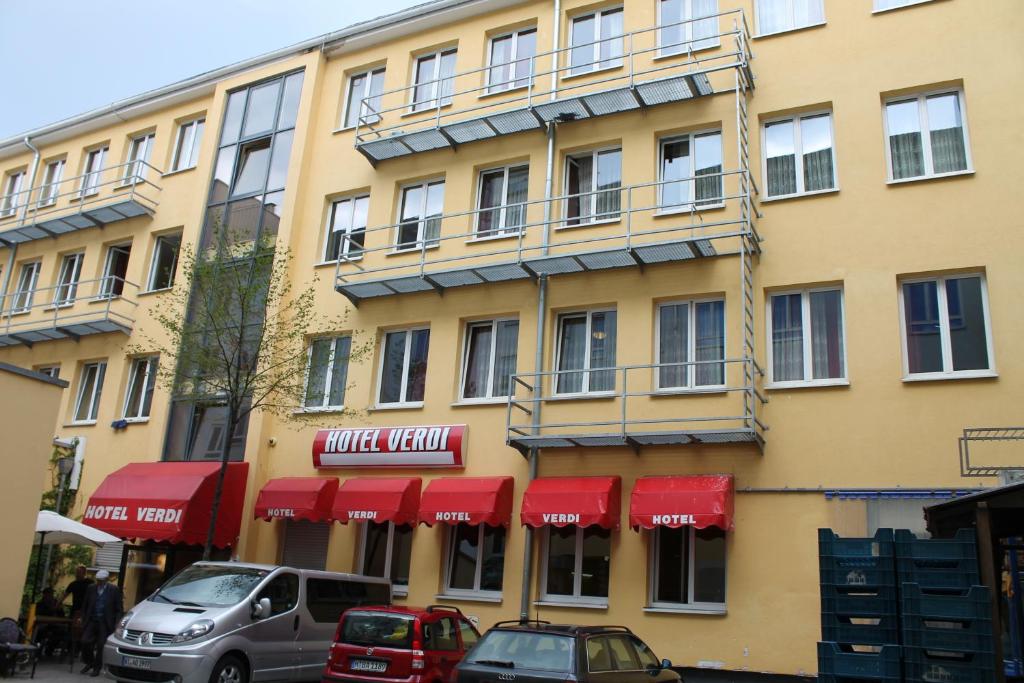 慕尼黑威尔第酒店的一座有红色遮阳篷的建筑和停在外面汽车