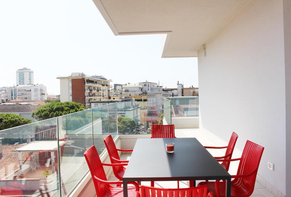 利多迪耶索罗Dainese Apartments, Casa Miriam的阳台上配有一张黑桌子和红色椅子