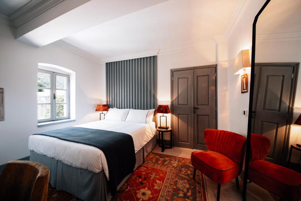 科托尔Palazzo Sbutega的一间卧室配有一张床和一张红色椅子