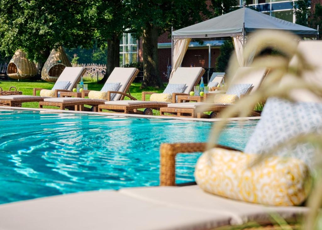 巴德茨维什安雅阁豪斯艾登齐罗曼蒂克酒店的游泳池旁的一排躺椅