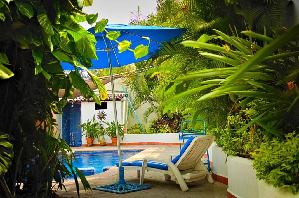 巴亚尔塔港Casa las Flores的游泳池旁的一对椅子和一把遮阳伞
