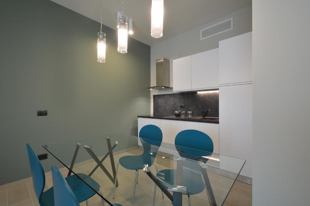 博尔加罗托里内塞ATMOSFERA APARTMENTS & SUITES的厨房配有玻璃桌和蓝色椅子