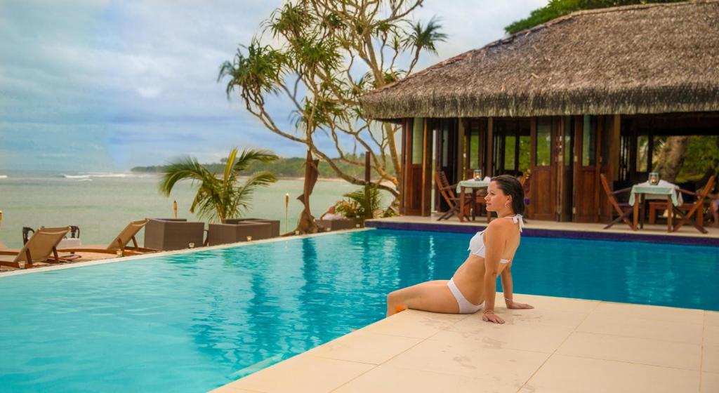 维拉港布雷卡斯海滩度假酒店的坐在游泳池边的比基尼的女人