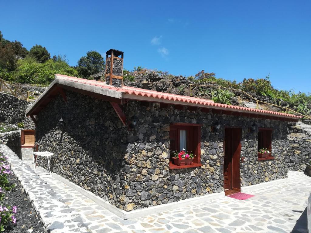 伊科德洛斯维诺斯Casas Rurales Los Guinderos的石屋,设有两扇窗户和石墙