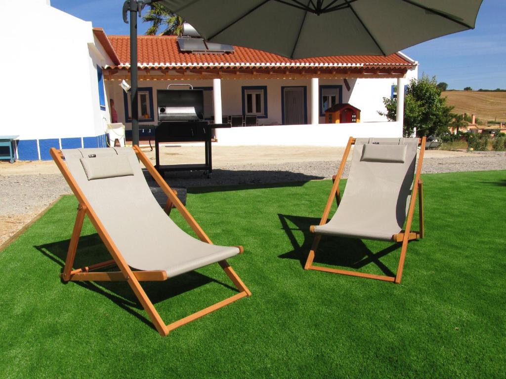 塞卡尔Casa do Chaparral campo e praia的两把草坪椅,坐在草地上,放在伞下