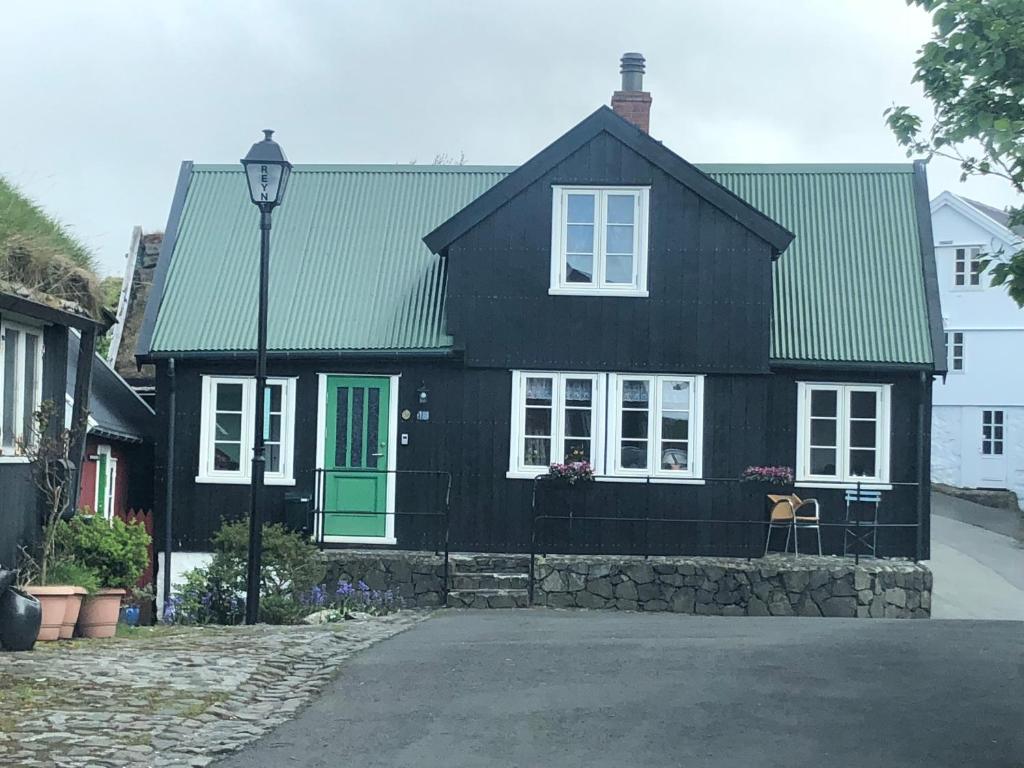 托尔斯港A pearl in the center of the center of Thorhavn的一间黑色的房子,设有绿门和街灯