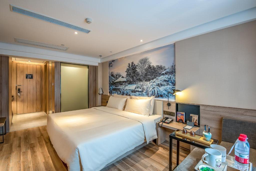 杭州杭州西湖湖滨亚朵酒店的卧室配有白色的床和墙上的绘画作品