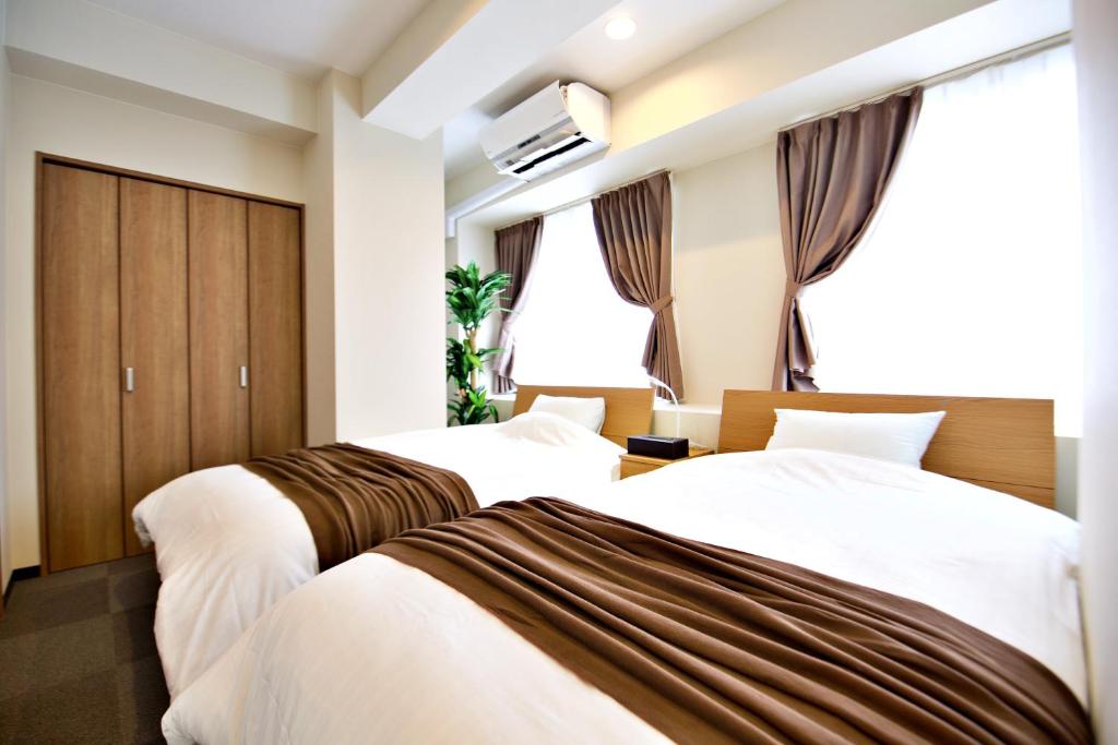 泉佐野KURA HOTEL IZUMISANO的酒店客房设有两张床和窗户。