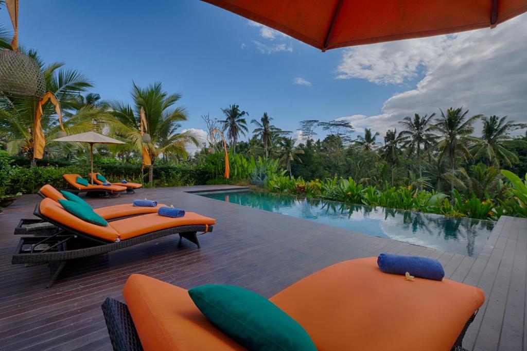 帕洋安Villa Tegal Tis Ubud - CHSE Certified的一个带橙色躺椅的游泳池,一个度假村