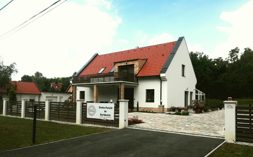 GyőrújbarátDreko Panzió & Borbisztró的白色的房子,有红色的屋顶和栅栏