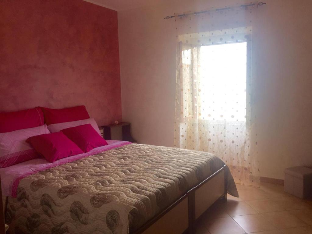 皮耶特拉佩尔托萨A due passi的一间卧室配有带粉红色枕头的床和窗户。