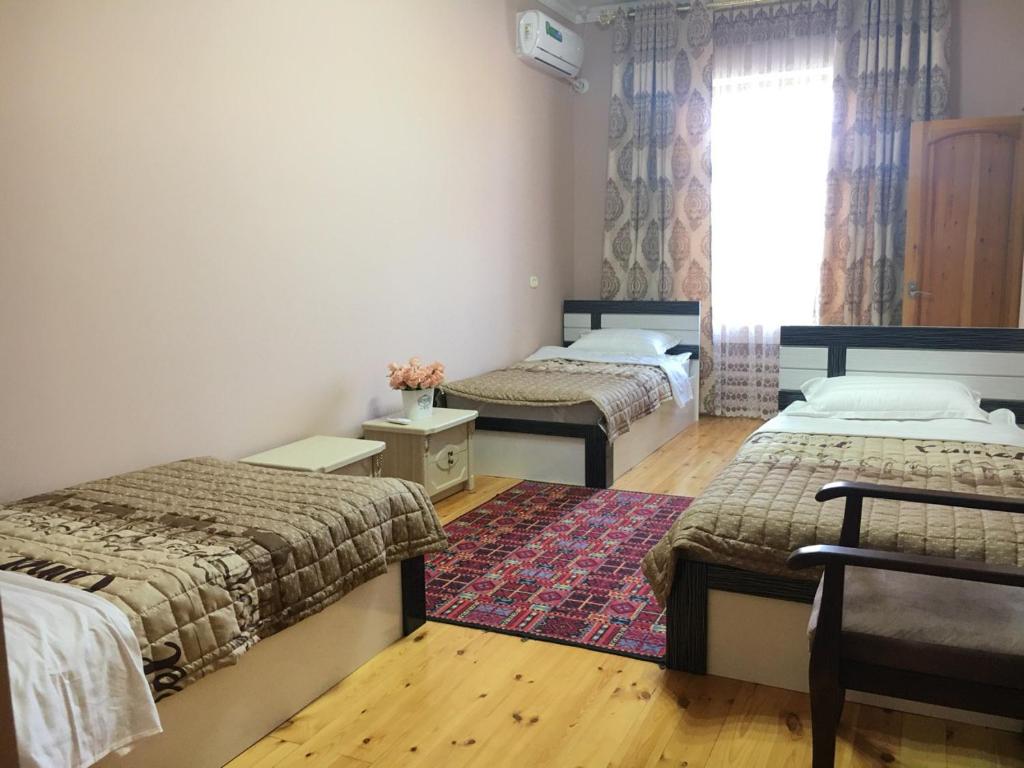 撒马尔罕Brown Hill的一间卧室设有两张床、一个窗户和一个地毯。