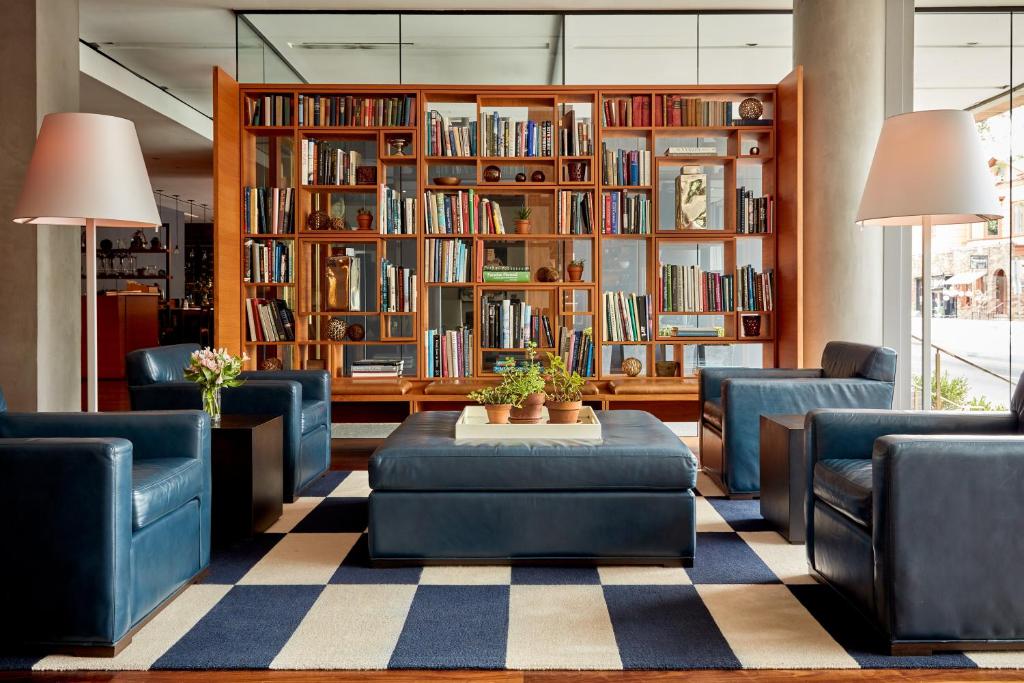 纽黑文The Study at Yale, Study Hotels的图书馆配有蓝色的椅子、桌子和书架