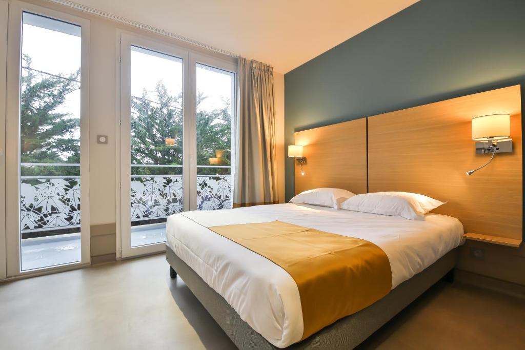圣伊莱尔德里耶Vent d'Eden Park Hôtel的一间卧室设有一张大床和两个窗户。