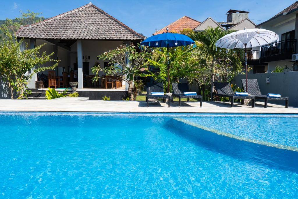 艾湄湾Bali Dive Resort Amed的一个带两把遮阳伞和房子的游泳池