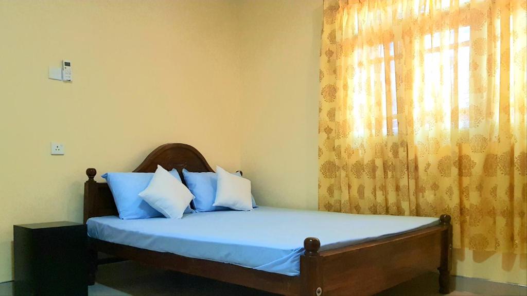 阿努拉德普勒Nimal's Home的一间卧室配有一张带蓝色床单的床和一扇窗户。