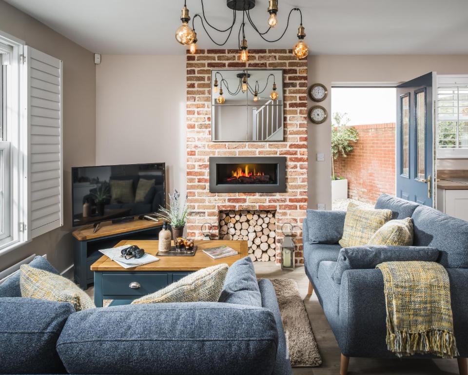 坎伯利Owlers Cottage的客厅设有蓝色的沙发和壁炉
