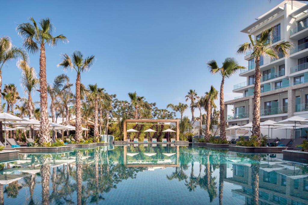 帕福斯Amavi, MadeForTwo Hotels - Paphos的棕榈树和建筑的度假游泳池