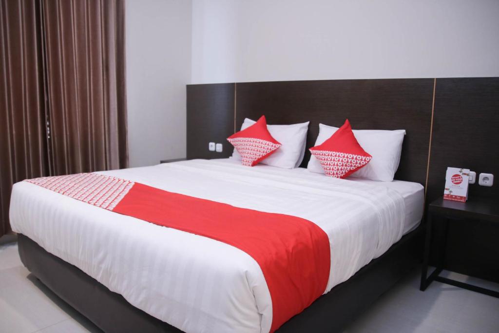 安汶Super OYO 1006 Azzahra Guest House Syariah的一间卧室配有一张带红色和白色枕头的大床