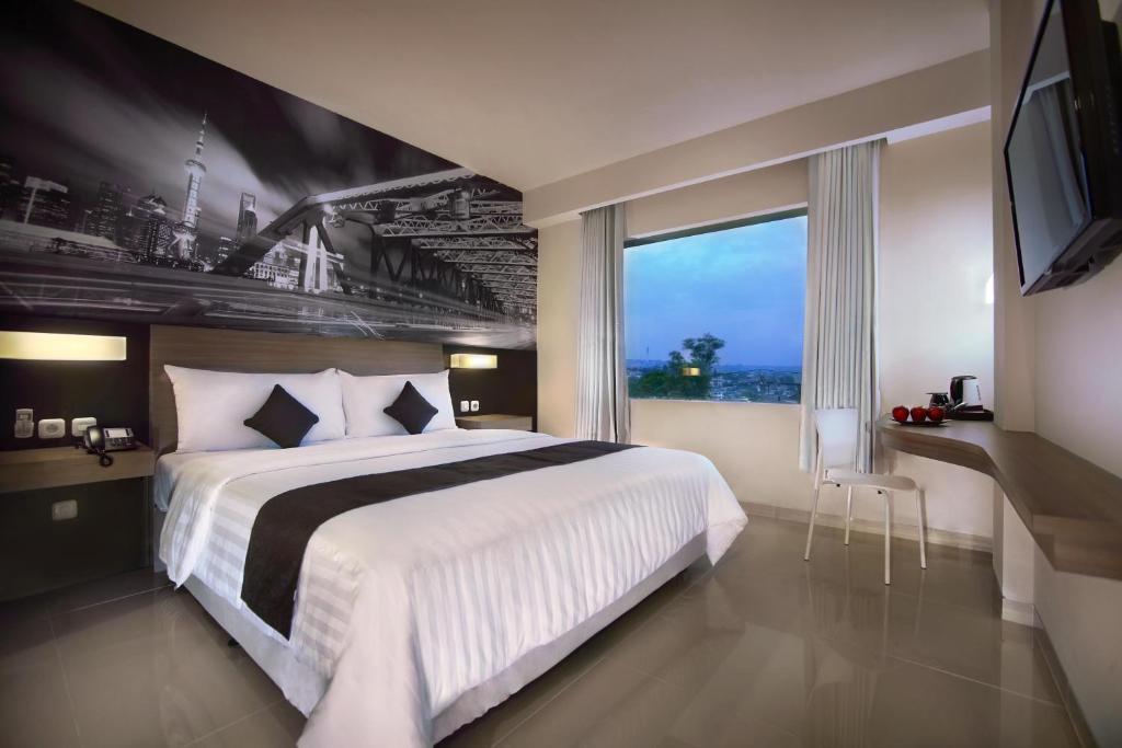 三宝垄Hotel Neo Candi Simpang Lima - Semarang by ASTON的一间卧室设有一张大床和一个大窗户