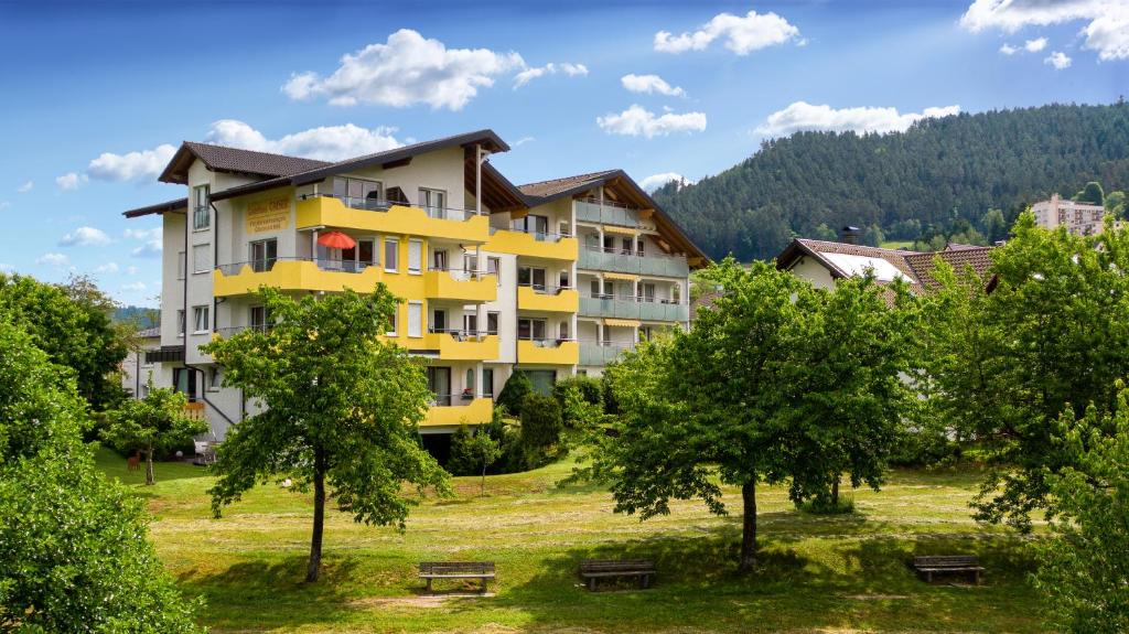 拜尔斯布龙Gästehaus Gaiser的一座黄色的公寓楼,位于树木繁茂的公园内