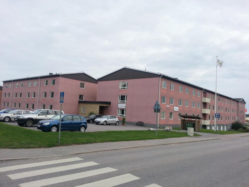 雪平Vandrarhem Köping的一座大型粉红色建筑,停车场内有汽车停放
