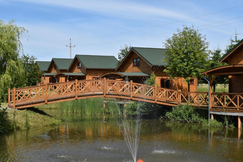 吉日茨科Orion Domki Letniskowe的一座房子前面的池塘上的木桥
