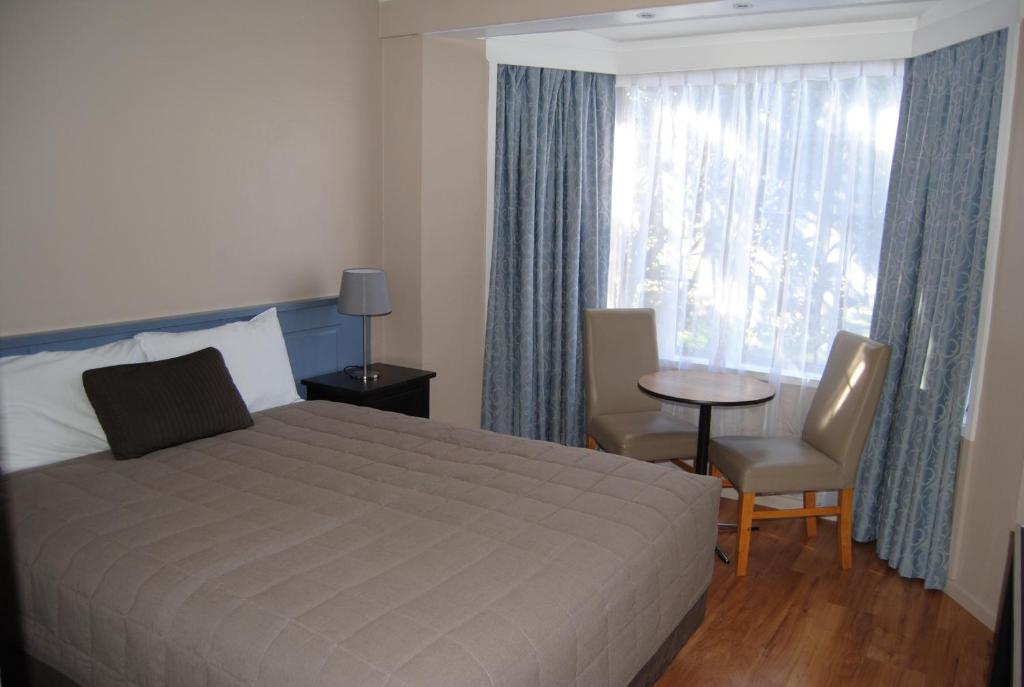 斯昆艾尔利之家汽车旅馆的一间卧室配有一张床、一张桌子和一个窗户。
