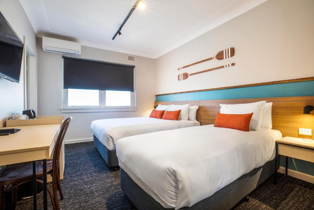 艾塔龙海滩Nightcap at Ocean Beach Hotel的酒店客房设有两张床、一张桌子和一张书桌。
