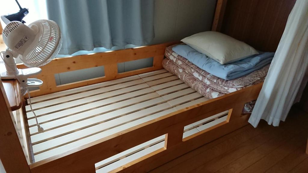 阿智村Guest house Minna no Ie的配有风扇的客房内的一张小床