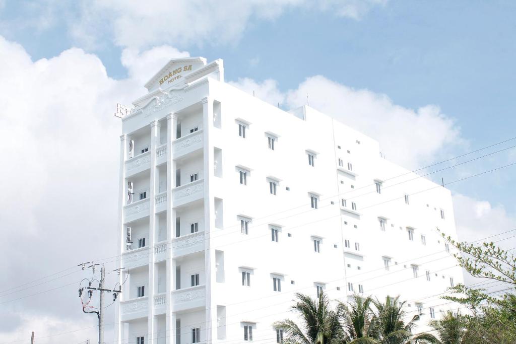 Xóm Nhà MátHoàng Sa Hotel的一座白色的建筑,前面有棕榈树