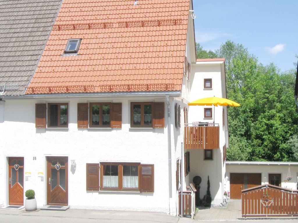 阿尔戈伊地区伊斯尼Ferienwohnung Wagner的白色的房子,有橙色的屋顶和雨伞