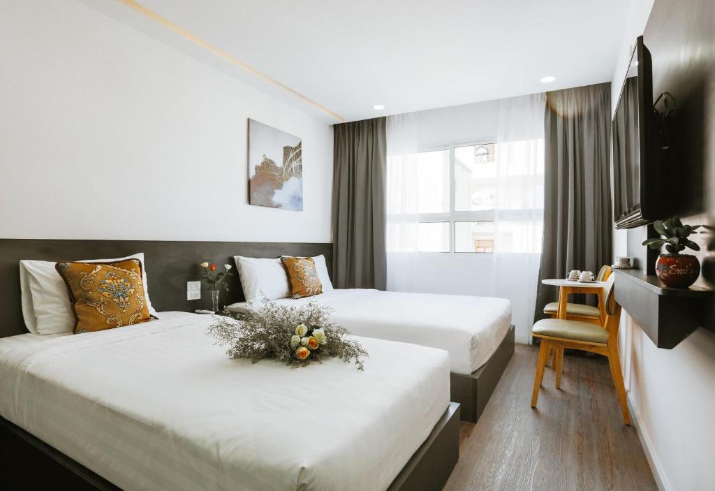 芽庄Larosa Hotel Nha Trang的酒店客房,配有两张带鲜花的床