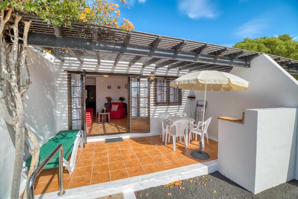 普拉亚布兰卡Ona Las Casitas的庭院配有遮阳伞和桌椅。
