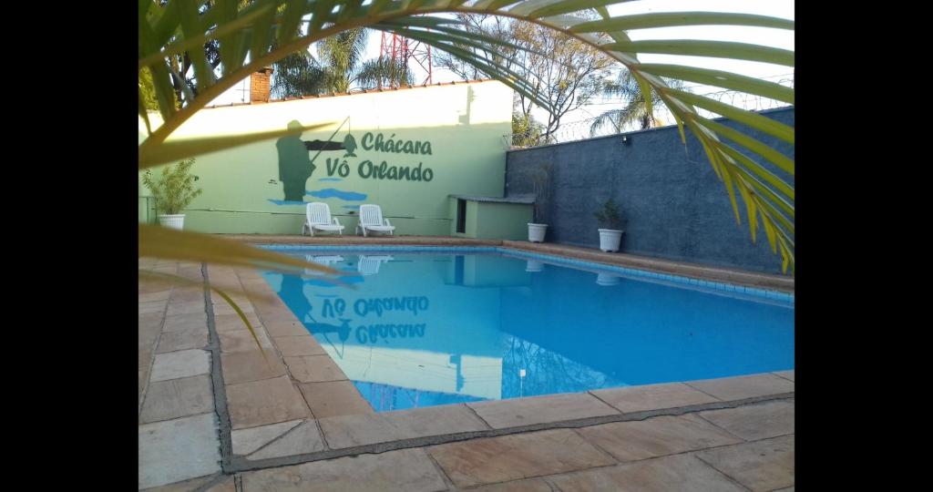 里奥克拉鲁Chácara Vô Orlando的一座带两把椅子的游泳池位于大楼旁
