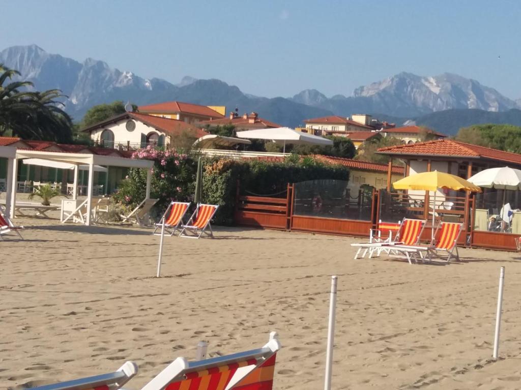 马里纳-迪-皮特拉桑塔Appartamento Versilia lungomare的海滩上的一组椅子和遮阳伞
