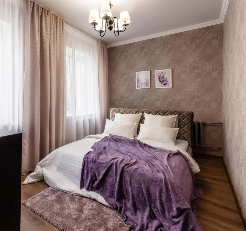 博布鲁伊斯克PaulMarie Apartments on Gogolya 39的一间卧室配有一张床铺,床上铺有紫色毯子
