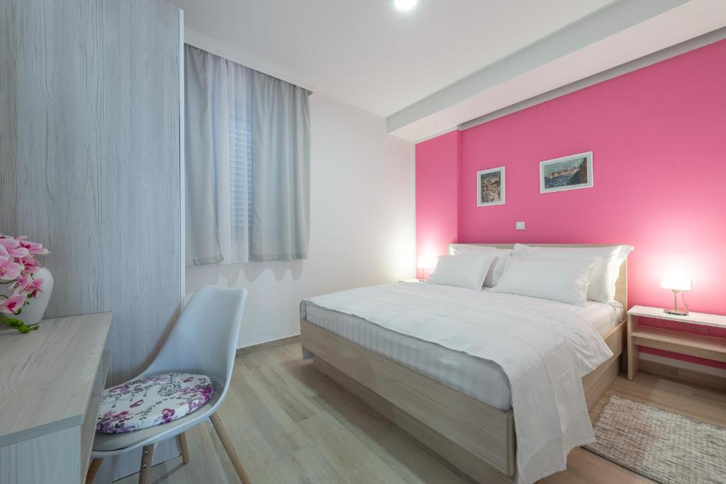 杜布罗夫尼克Apartments MoniDuL的卧室设有粉红色的墙壁、一张床和一张书桌