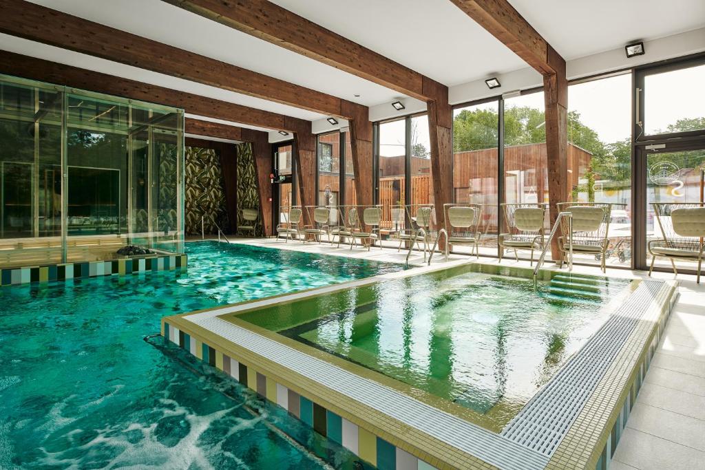 派尔努Wasa Resort Hotel, Apartments & SPA的大楼内带椅子的大型游泳池