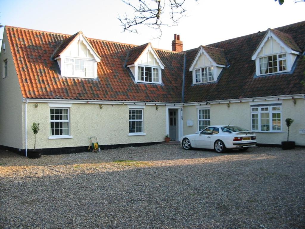 诺里奇Home farm cottage Guest House的前面有一辆汽车停放的白色房子