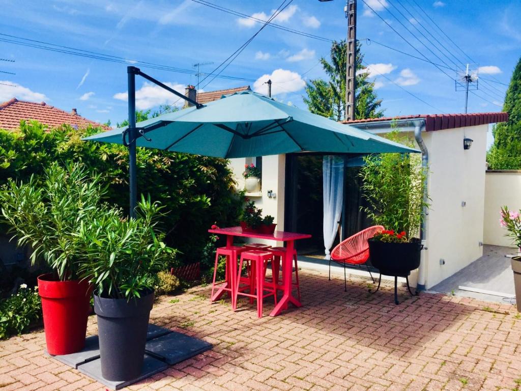 博讷La Cuisine d'été de BeaunAmour的露台上配有红色桌子和蓝色遮阳伞