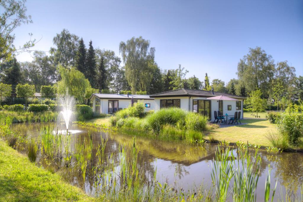 瓦赫宁根TopParken – Recreatiepark de Wielerbaan的池塘旁的喷泉房子