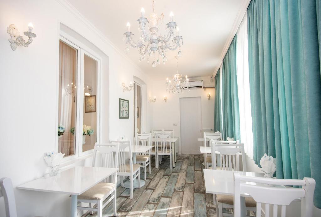 第比利斯洛厄尔酒店的餐厅配有白色的桌椅和吊灯